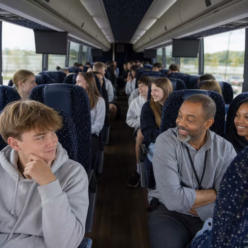 Group boarding a white charter bus for School Transportation transportation in Newark